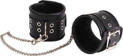 Кожаные черные оковы с широким ремешком, соединенные цепочкой Изготавливаются из натуральной кожи с велюровой подкладой. При изготовлении использована фурнитура с никелевым покрытием. Между слоем основы и подкладой проложена мягкая прокладка. Соединяются между собой цепочкой с двумя карабинами на концах. Не нарушают кровообращение, надёжно фиксируются щиколотках. Размер универсальный. Длина цепочки - 35 см. Страна: Россия. Материал: натуральная кожа.