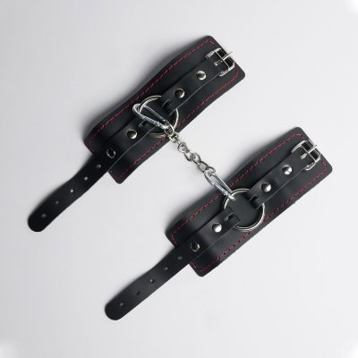 Черные кожаные наручники с красной строчкой Встречайте наручники с лаконичным и стильным дизайном , которые станут вашим универсальным выбором для создания особой атмосферы. Эти наручники — это идеальное сочетание комфорта, функциональности и элегантности, созданное для тех, кто ценит простоту и безупречный вкус. Изделие выполнено из одного слоя натуральной кожи с мягким ремешком и стальным кольцом , которое добавляет конструкции прочности и современный шарм. Декоративная строчка красного цвета по краям подчеркивает стильный дизайн и добавляет изделию игривости. В комплект входит соединительный элемент из кожи с двумя надежными карабинами , которые обеспечивают стабильность и контроль. Общая длина изделия составляет 28 см , а каждая манжета имеет размеры 18,5 х 7 см , что делает их универсальными и подходящими для любого типа использования (от 19 до 27 см). Благодаря своей универсальности, эти наручники подойдут как для любовных игр, так и для завершения вашего образа в качестве модного аксессуара. Упаковка? Она тоже часть удовольствия! Наручники доставляются в фирменной упаковке с брендированной деревянной подложкой, которая не только защищает изделие, но и делает его идеальным подарком для особого человека… или для себя любимого(-ой). Длина манжет - 18,5 см, ширина - 7 см. Страна: Россия. Материал: натуральная кожа.