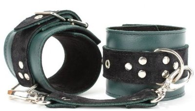 Изумрудные оковы на ноги Ladys Arsenal на карабинах Оковы выполнены из натуральной кожи изумрудного цвета. Изделие декорировано ремнями из замши черного цвета. Обратная сторона изделия тоже выполнена из черной замши. По середине аксессуара расположено полукольцо из сварной фурнитуры. Оковы надежно фиксируются пряжками и ремнями, позволяющими выбрать нужный размер, подойдут на обхват от 20 до 29 см. Кожаное соединение на карабинах фиксирует оковы вместе. Стильный аксессуар отлично подходят для воплощения эротических БДСМ игр. Ширина - 6 см. Длина соединения - 20 см. Страна: Россия. Материал: натуральная кожа.